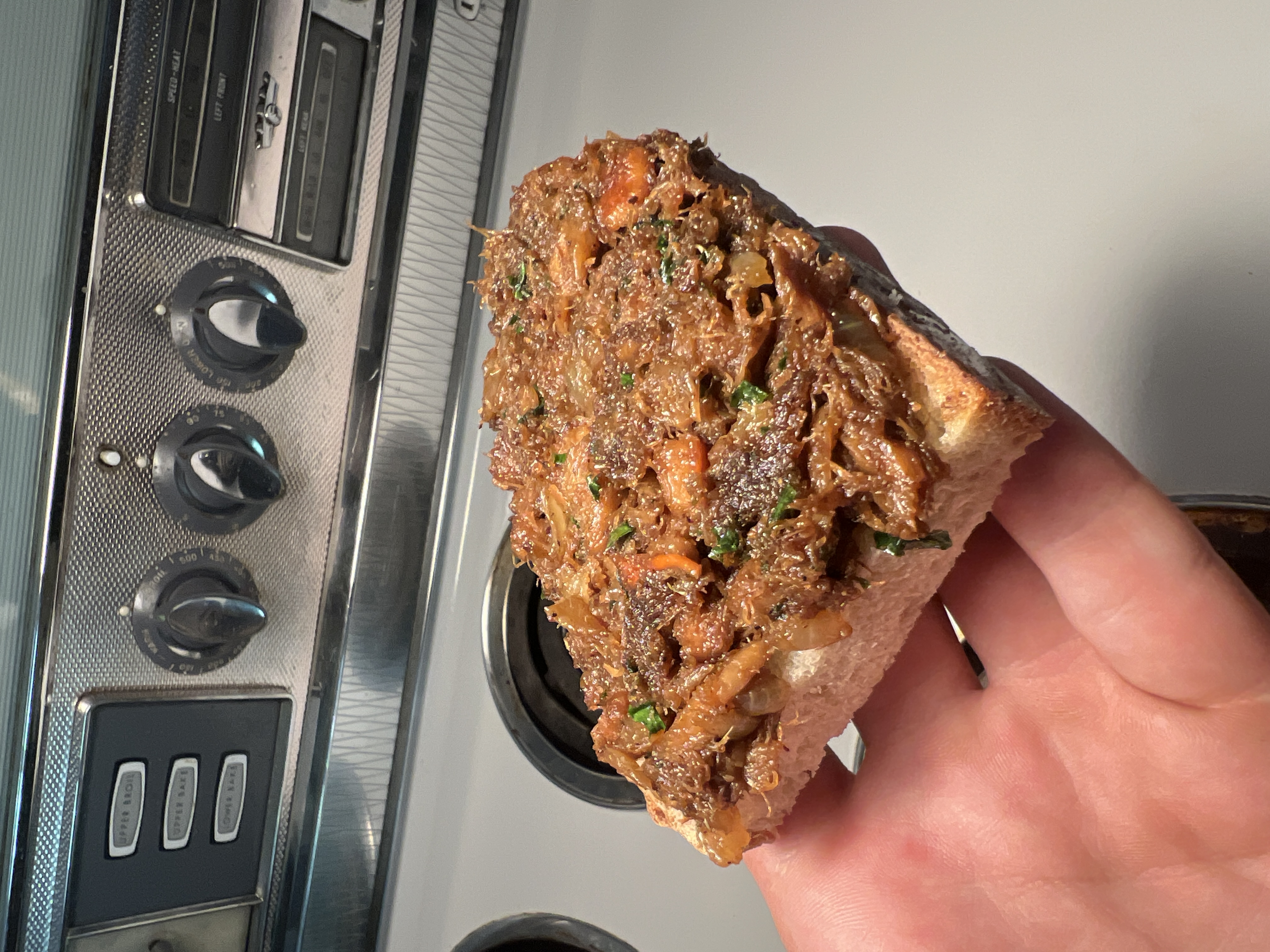 A piece of toast topped with a savory mushroom mixture held in a hand.